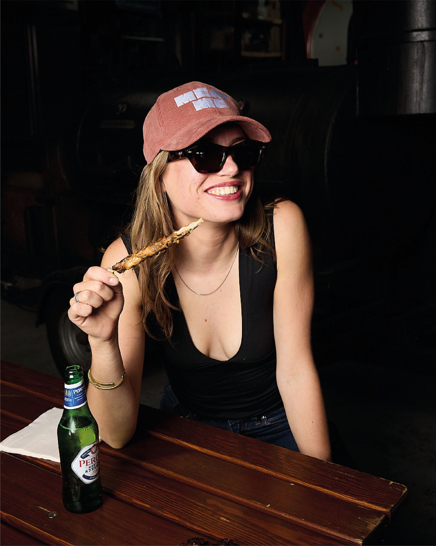 Vrouw met spies en een flesje bier aan een houten tafel